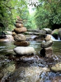 Close-up of smooth stones stacked beside a gently flowing water feature.