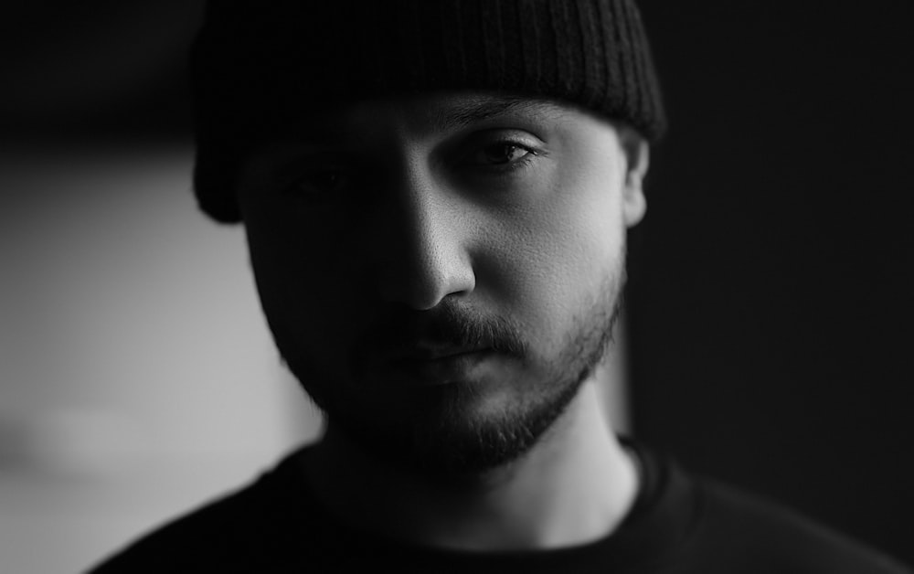 a black and white photo of a man wearing a beanie