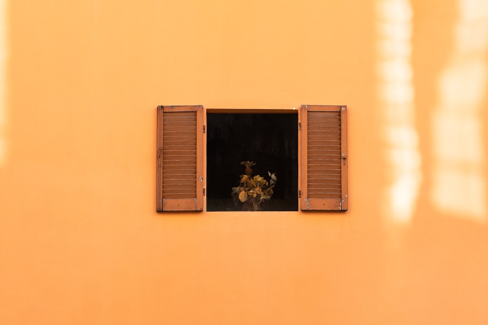 a yellow building with a window and shutters