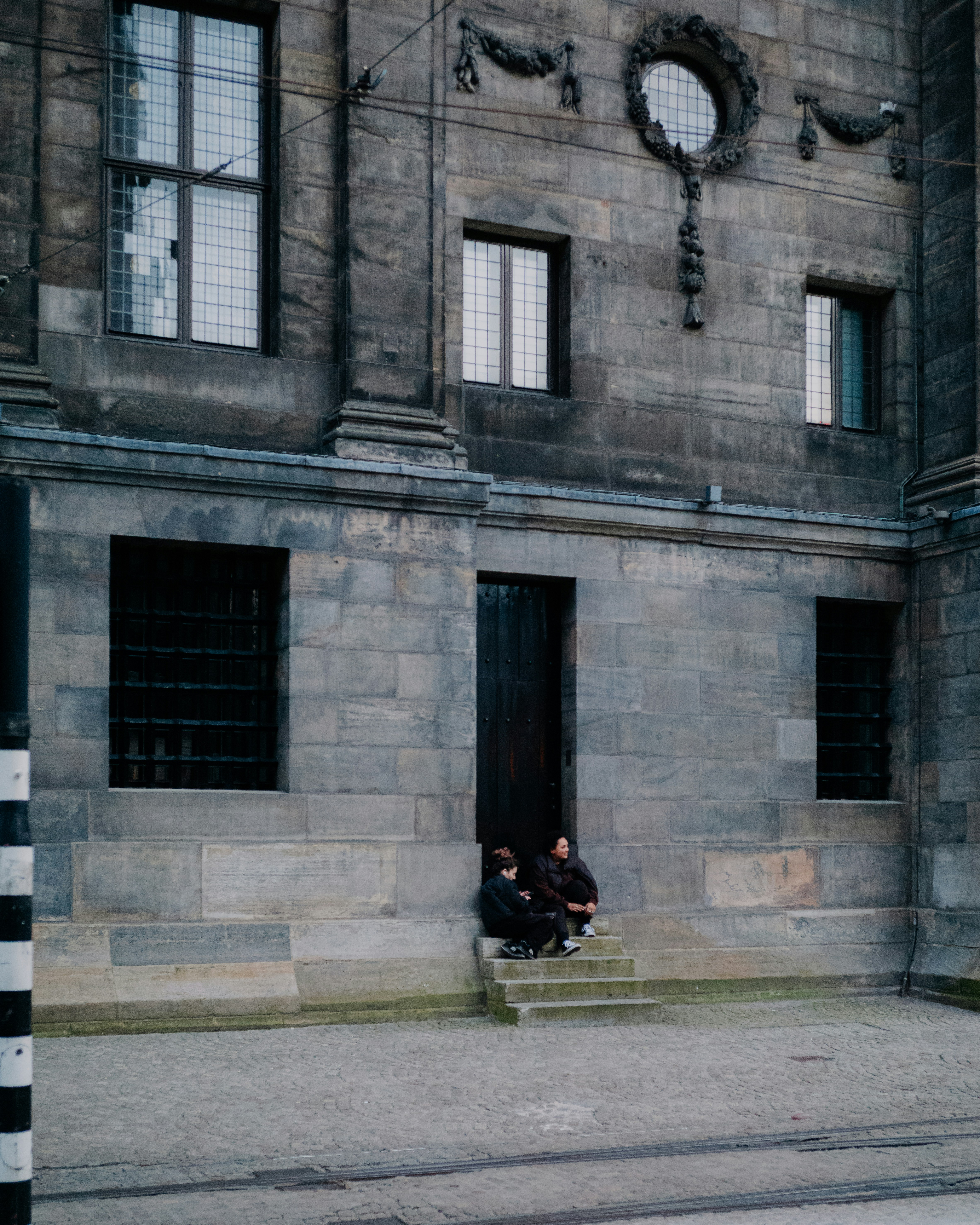 two people sitting on steps in front of a building