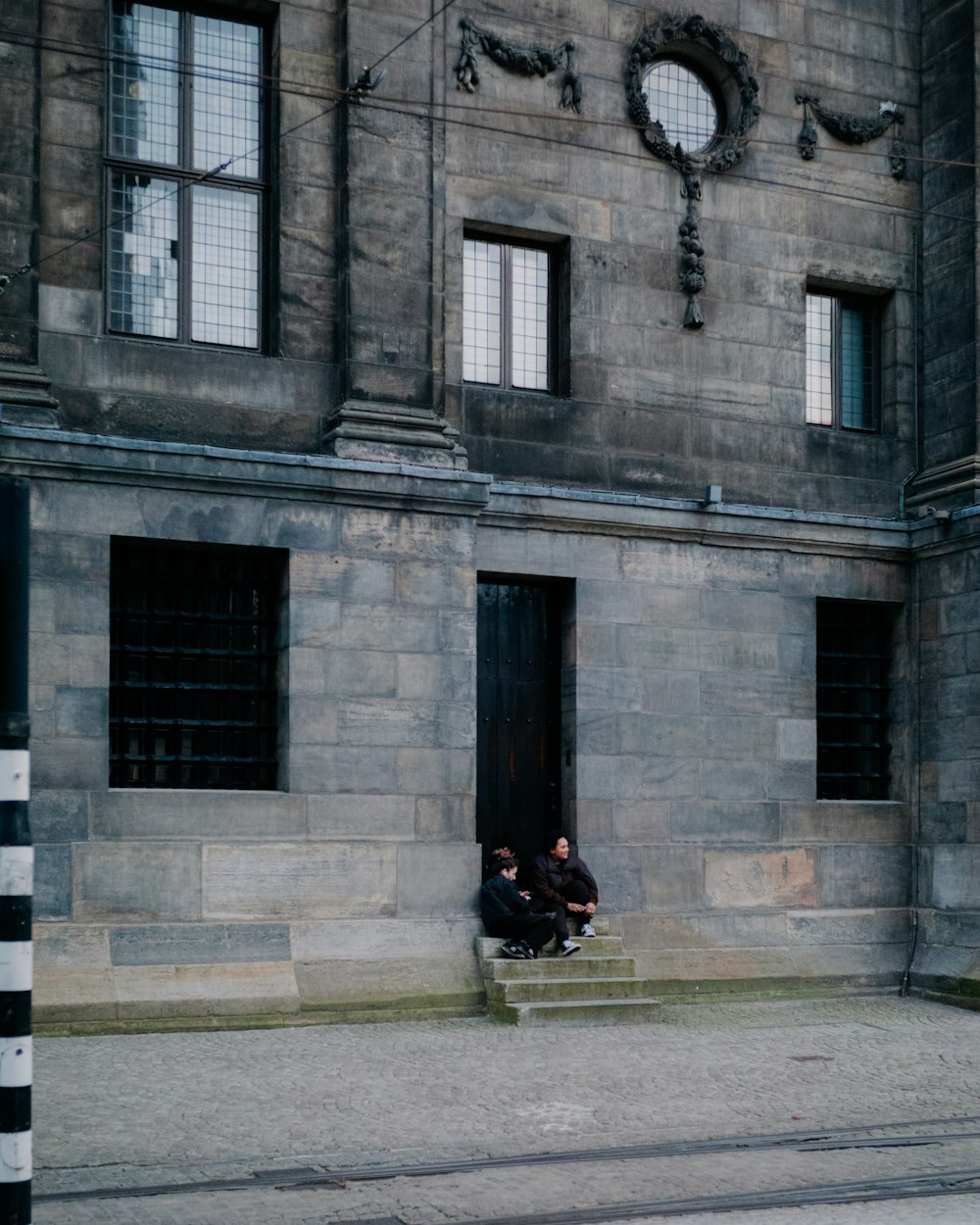 two people sitting on steps in front of a building