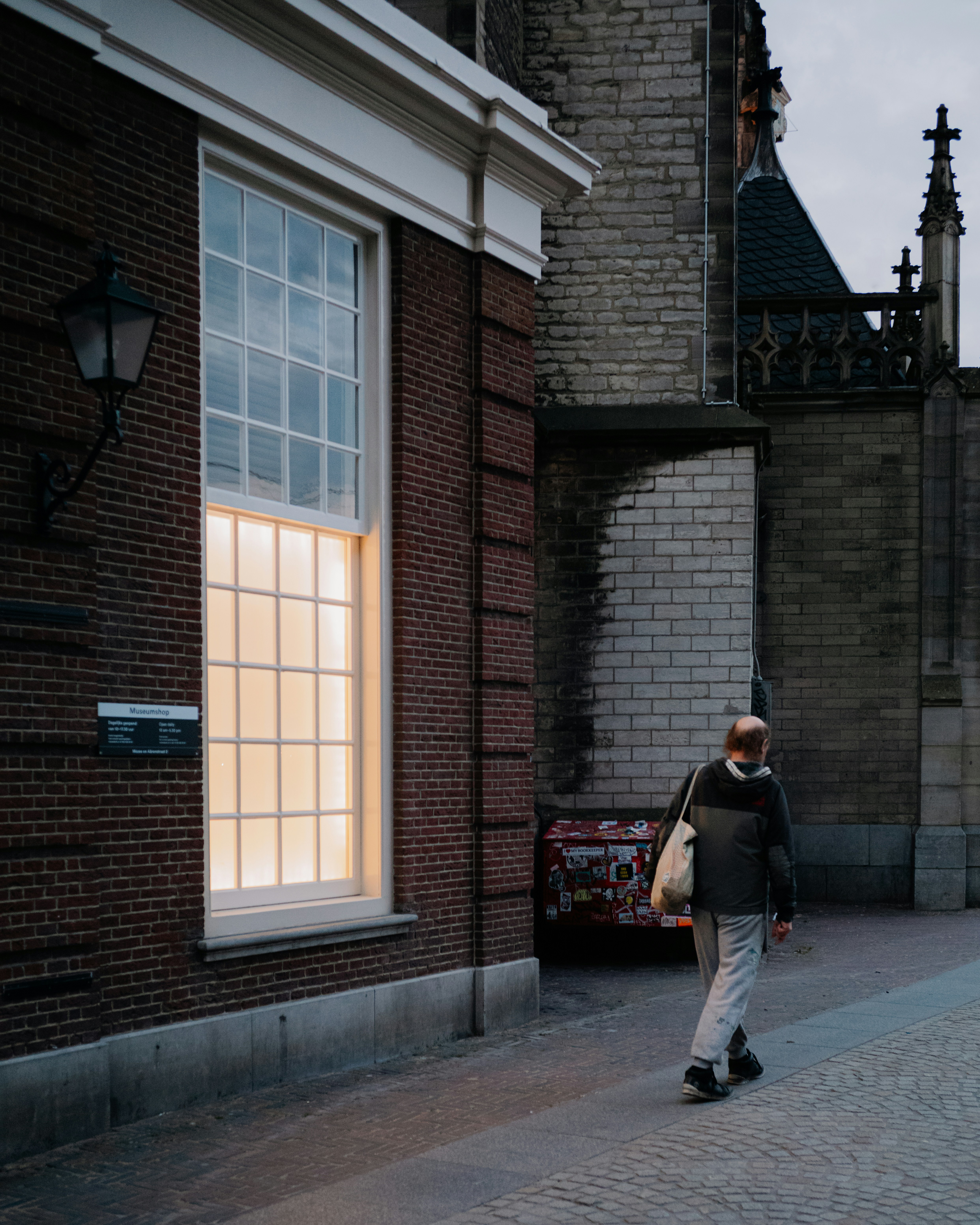 a man walking down a street next to a tall brick building