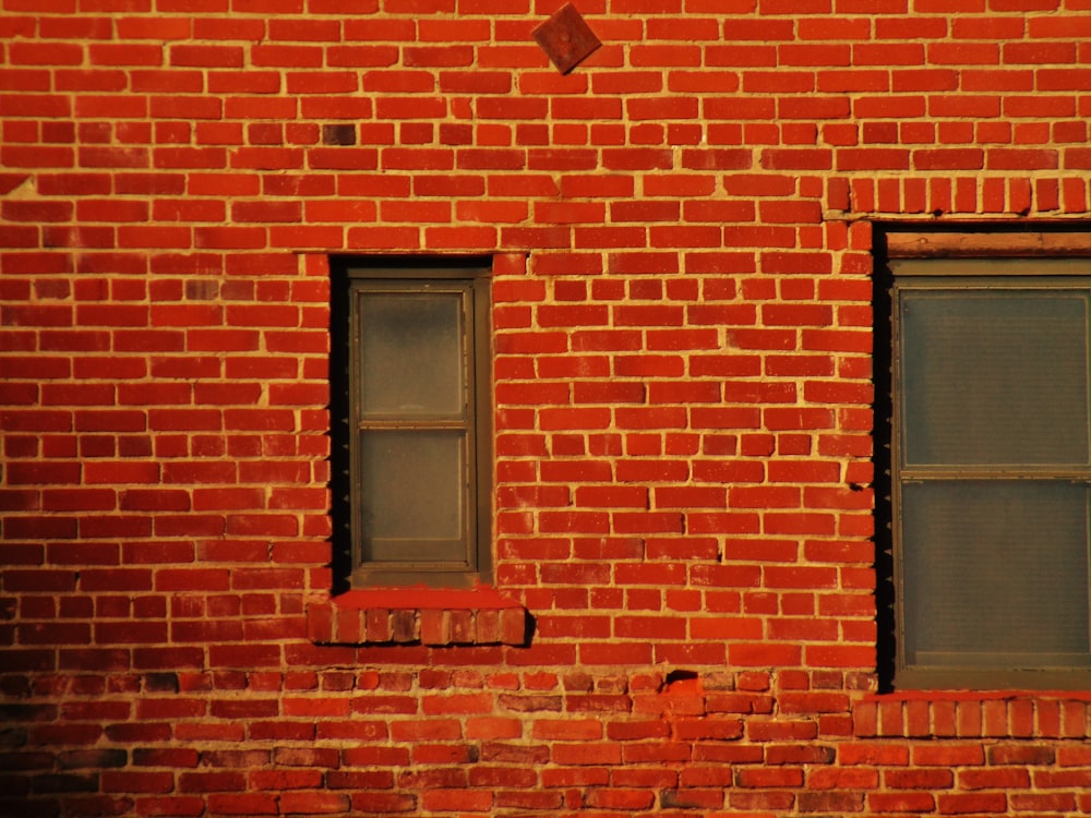 a red brick building with two windows and a stop sign