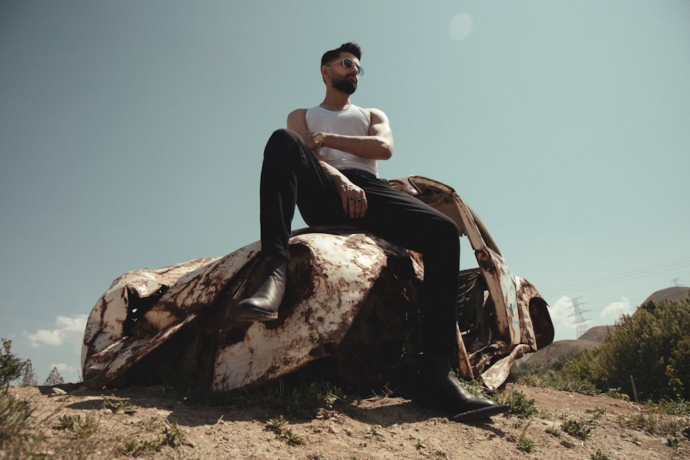 a man sitting on top of a rusted motorcycle