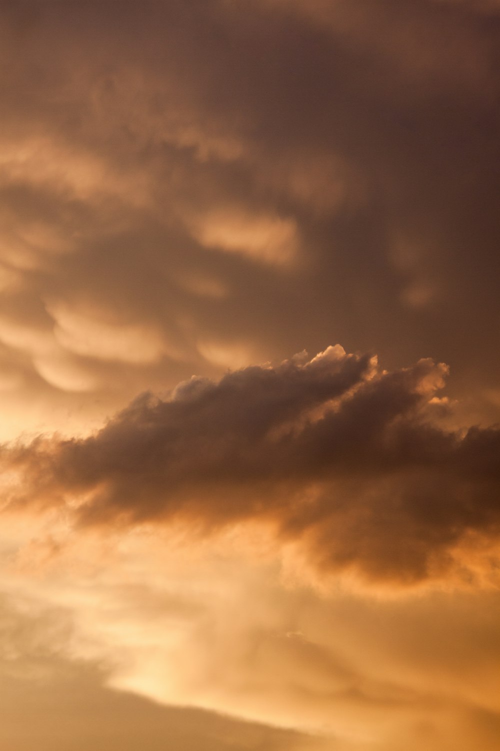 a plane flying through a cloudy sky at sunset