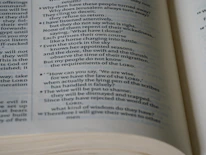 Close-up of hands holding a tablet showing an e-book with biblical teachings.