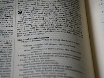 An open page of a book, likely a Bible, with text printed in columns. The section features prominent headings and verse numbers, with some words highlighted in bold.