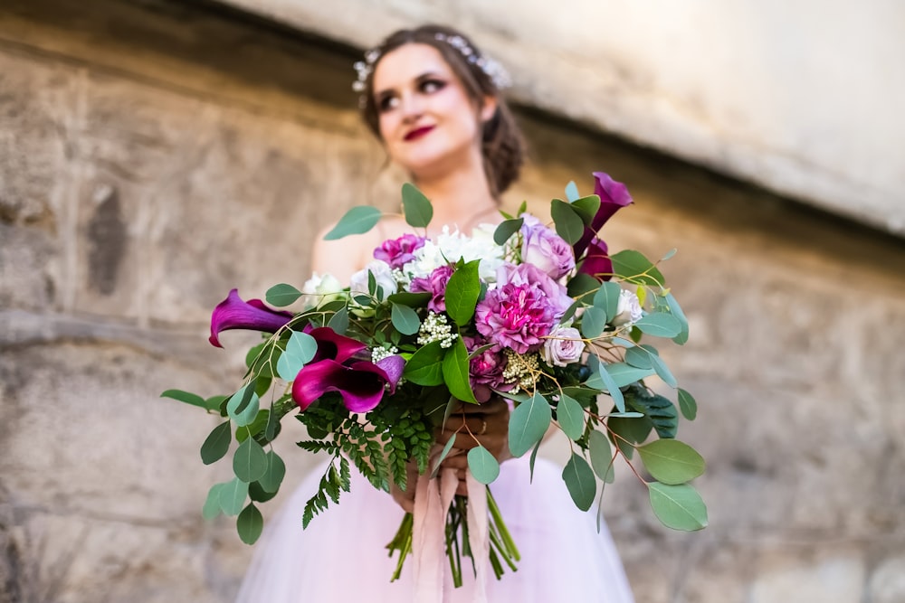 a woman in a wedding dress holding a bouquet of flowers