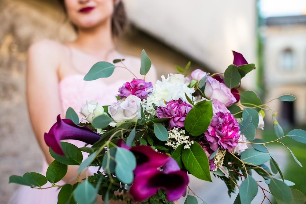 a woman in a pink dress holding a bouquet of flowers