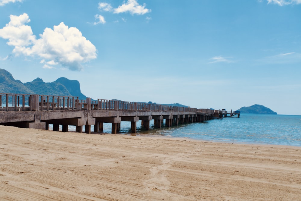 a long wooden pier sitting on top of a sandy beach