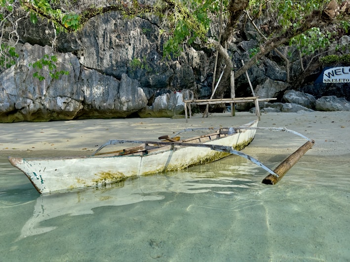 a boat sitting on top of a sandy beach