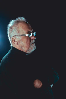 a man with a beard and glasses standing in the dark