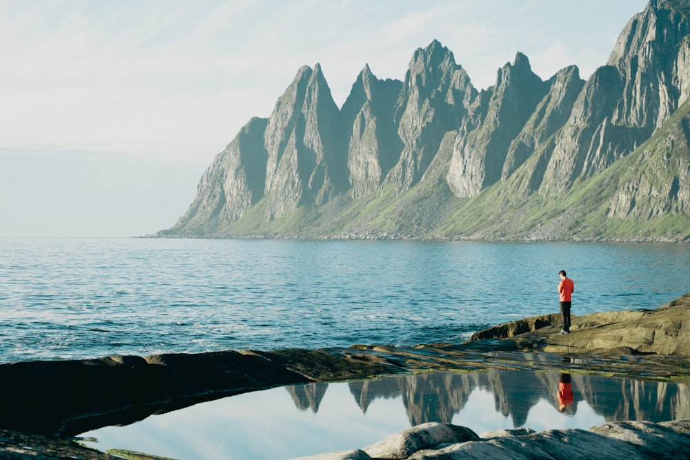 a man standing on a rock next to a body of water