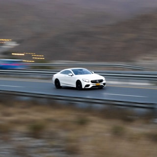 A high-performance sports car speeding along a scenic Dubai highway.