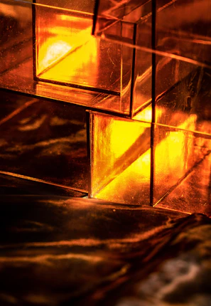 Close-up of a glowing golden 3D abstract shape with glassmorphic reflections.