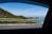 A friendly driver assisting passengers with their luggage near a scenic coastal road.