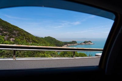 A scenic view of a car driving along a lush Bali coastline at sunset.