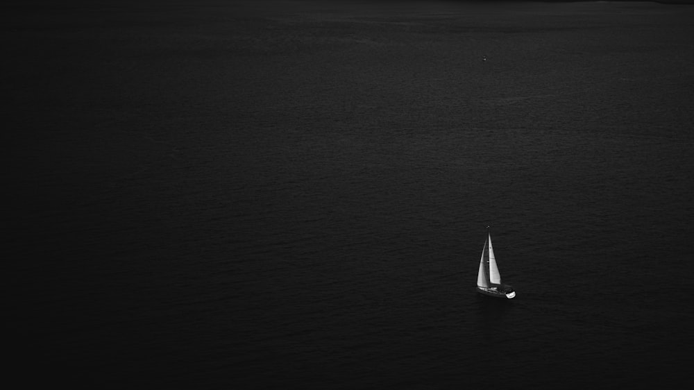 a lone sailboat in the middle of a body of water