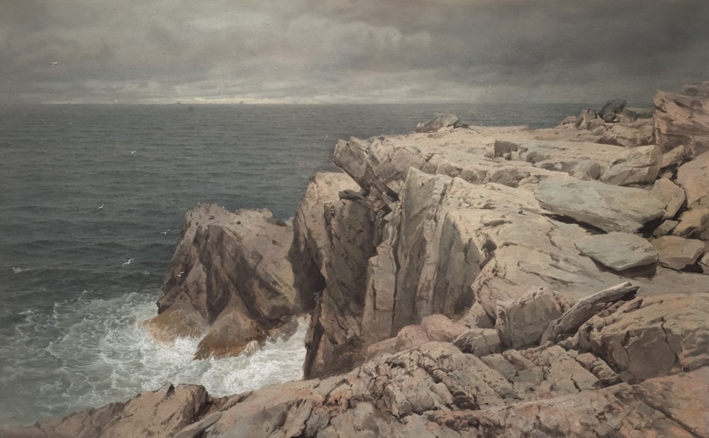 Ein Gemälde einer felsigen Küste mit Wellen, die gegen die Felsen schlagen