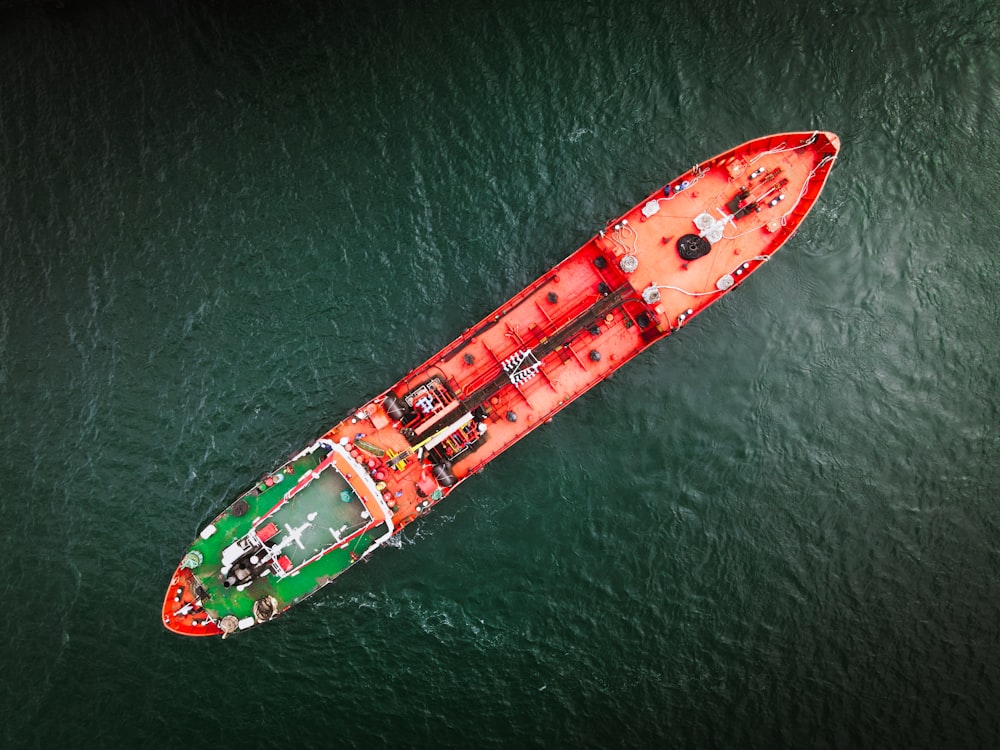 a green and red boat floating on top of a body of water