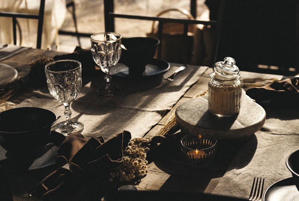 a wooden table topped with dishes and glasses