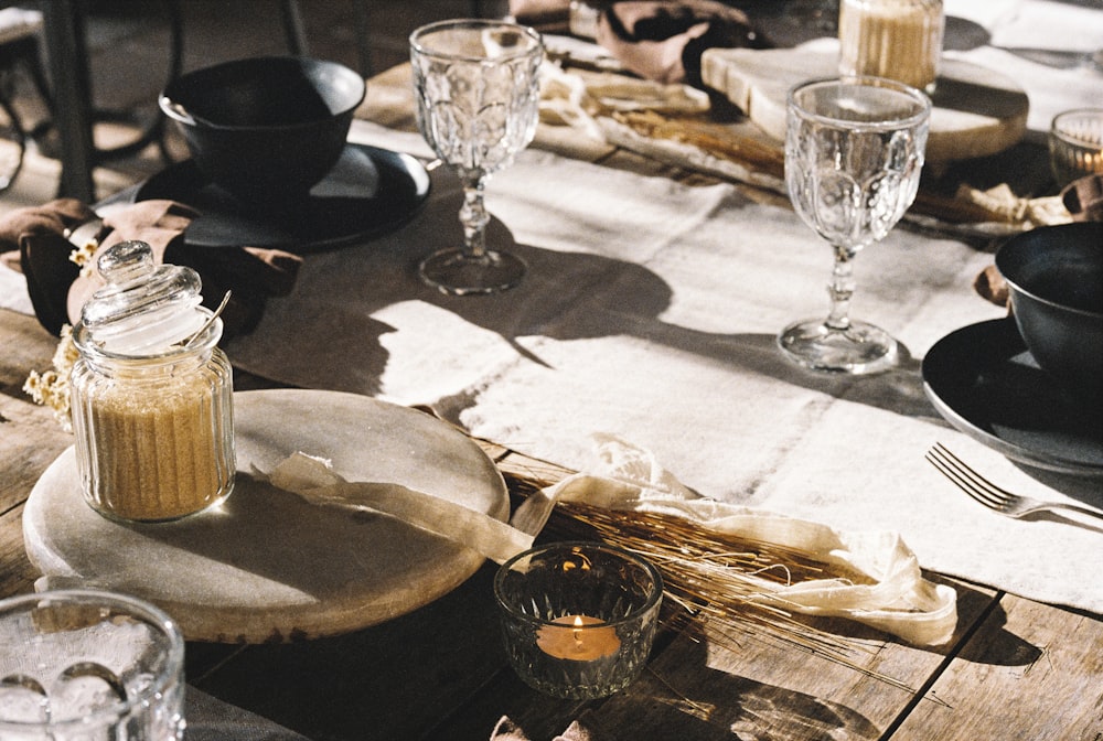 a wooden table topped with plates and glasses