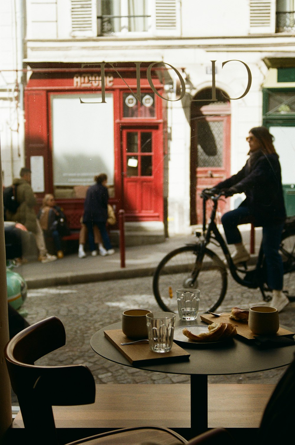 a woman riding a bike down a street next to a table