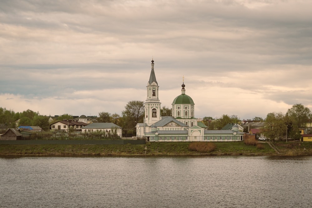 a large white building with a green dome next to a body of water
