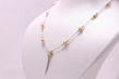 Elegant gold necklace with intricate design displayed on a minimalist white bust.