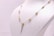 A delicate chain necklace displayed on a white mannequin bust. The necklace features gold bead elements distributed evenly along its length, with a central bead from which two chains hang down symmetrically.