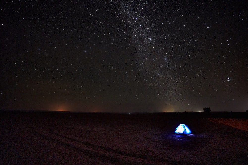 a tent in the middle of a field under a night sky