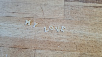 Individual pasta letters are arranged on a wooden surface to form the words 'MY LOVE'.