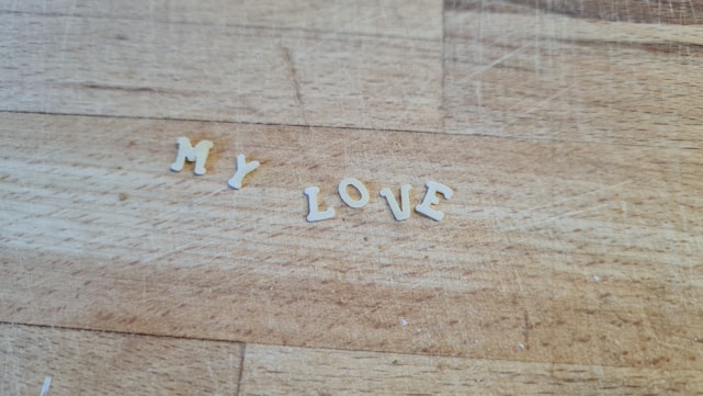 Individual pasta letters are arranged on a wooden surface to form the words 'MY LOVE'.
