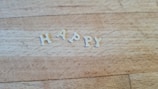 Letters spelling out the word HAPPY arranged on a wooden surface.