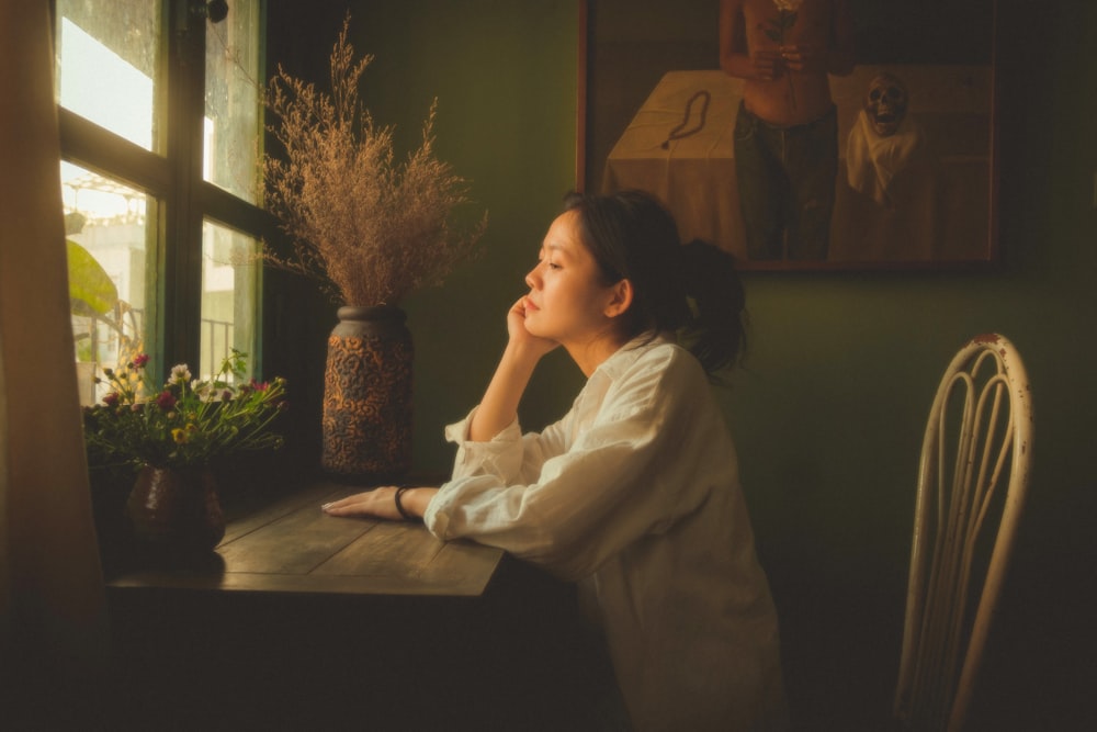 a woman sitting at a table looking out a window