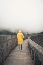 a person in a yellow jacket walking across a bridge
