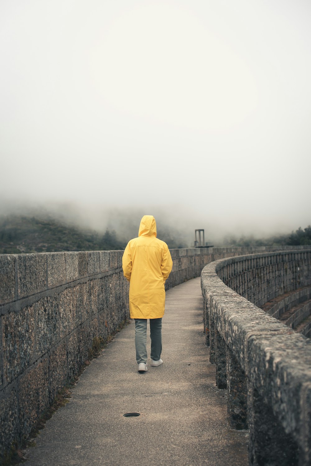 a person in a yellow jacket walking across a bridge