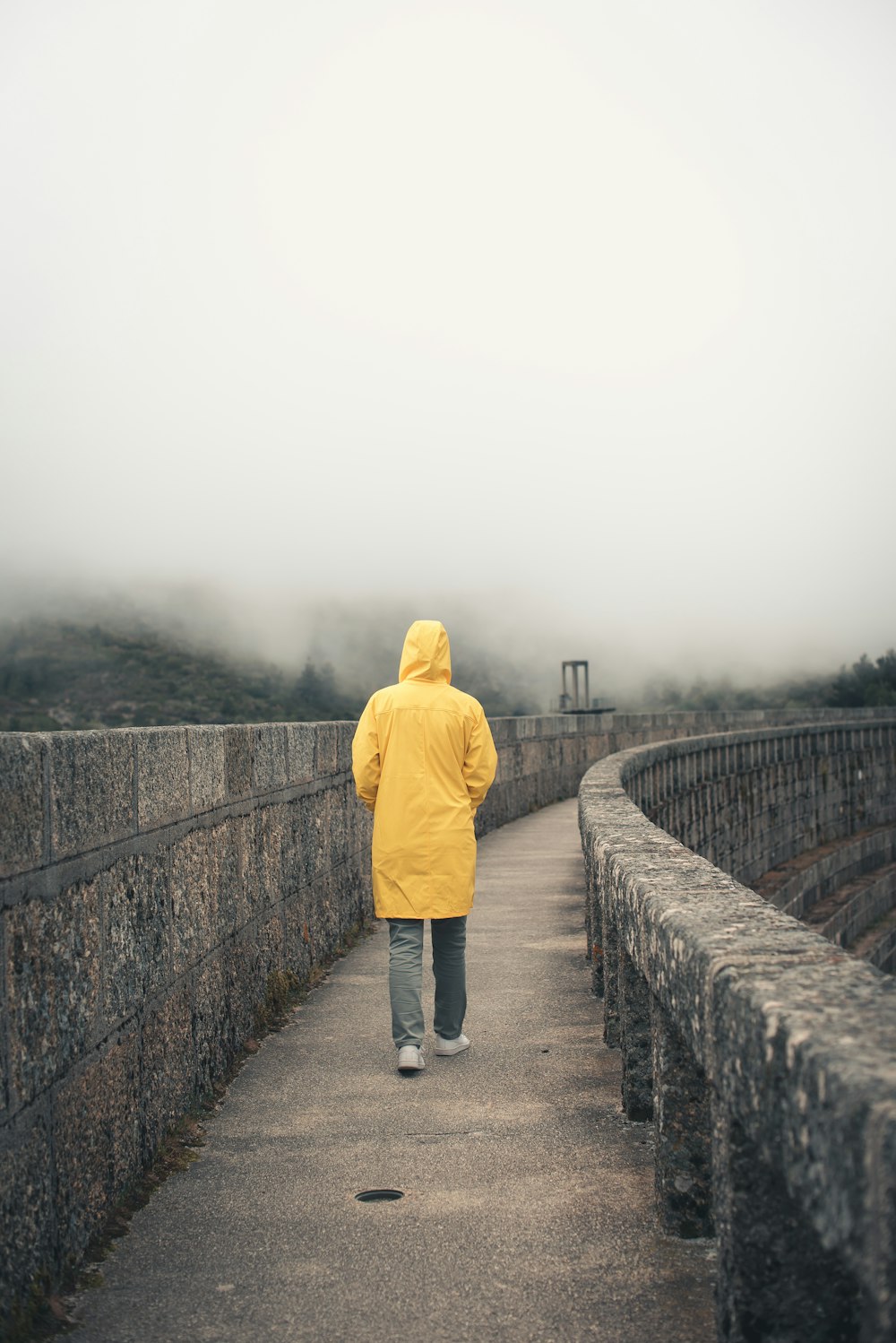 Eine Person in einer gelben Jacke, die über eine Brücke geht