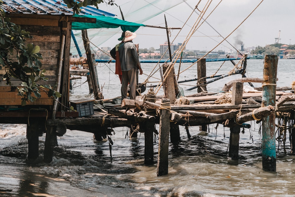 a man standing on a wooden dock next to a body of water