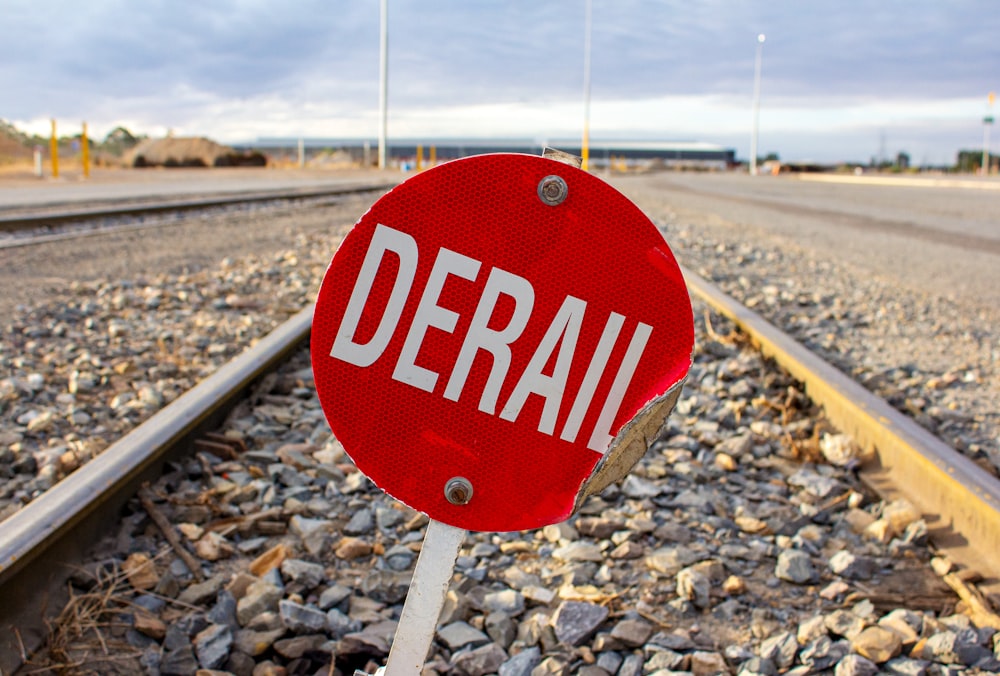 a red stop sign sitting on the side of a train track