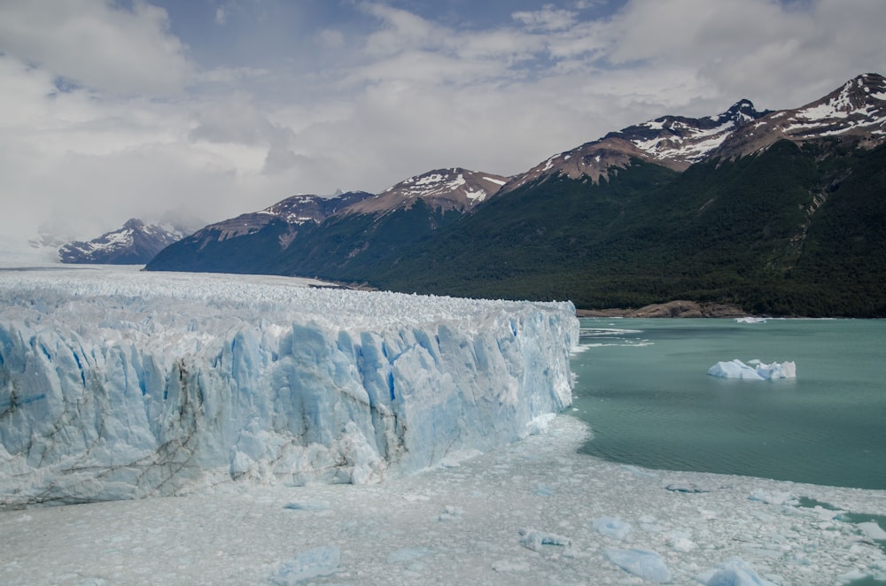 a large glacier with mountains in the background