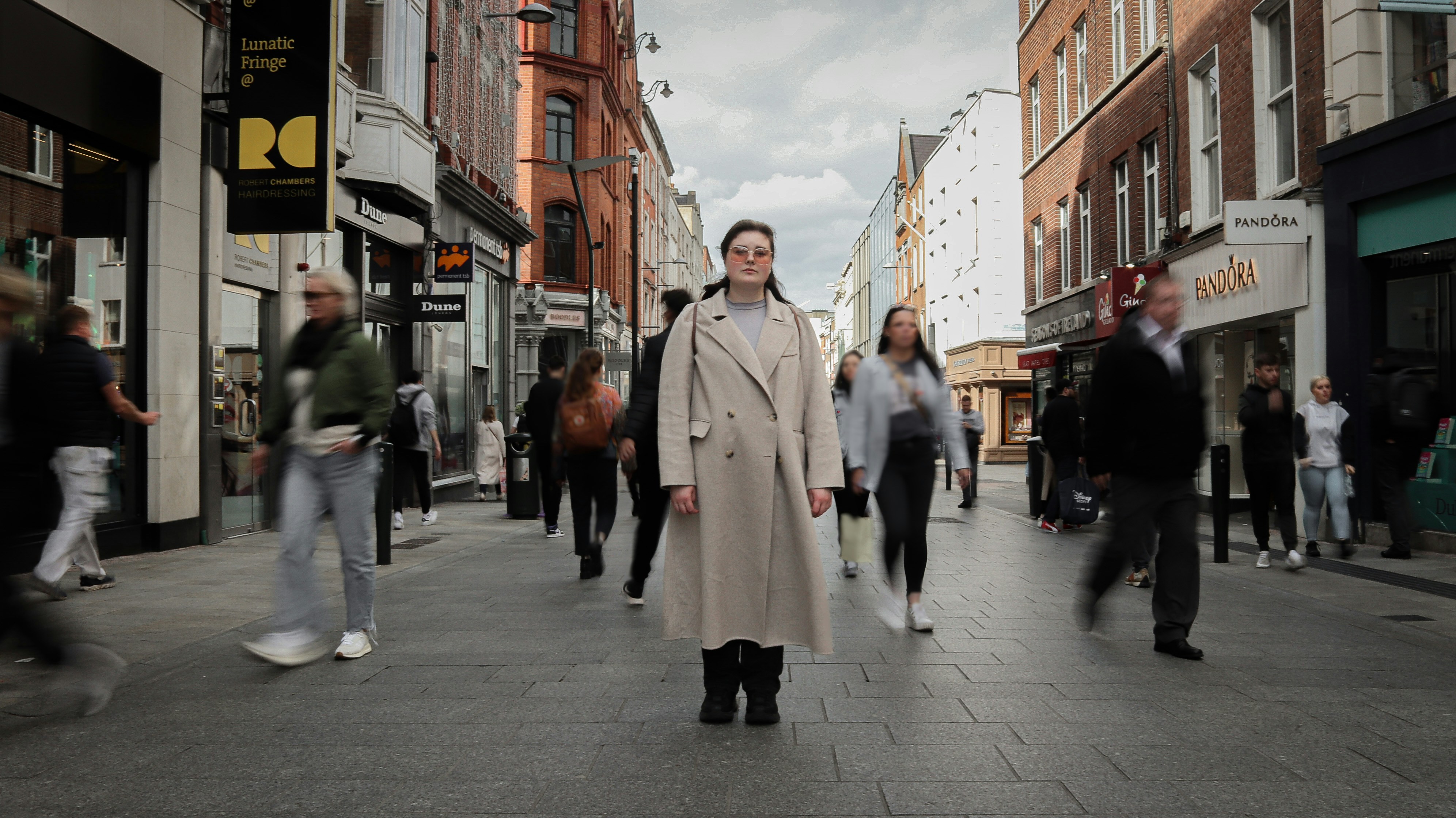A man in a trench coat walking down a street