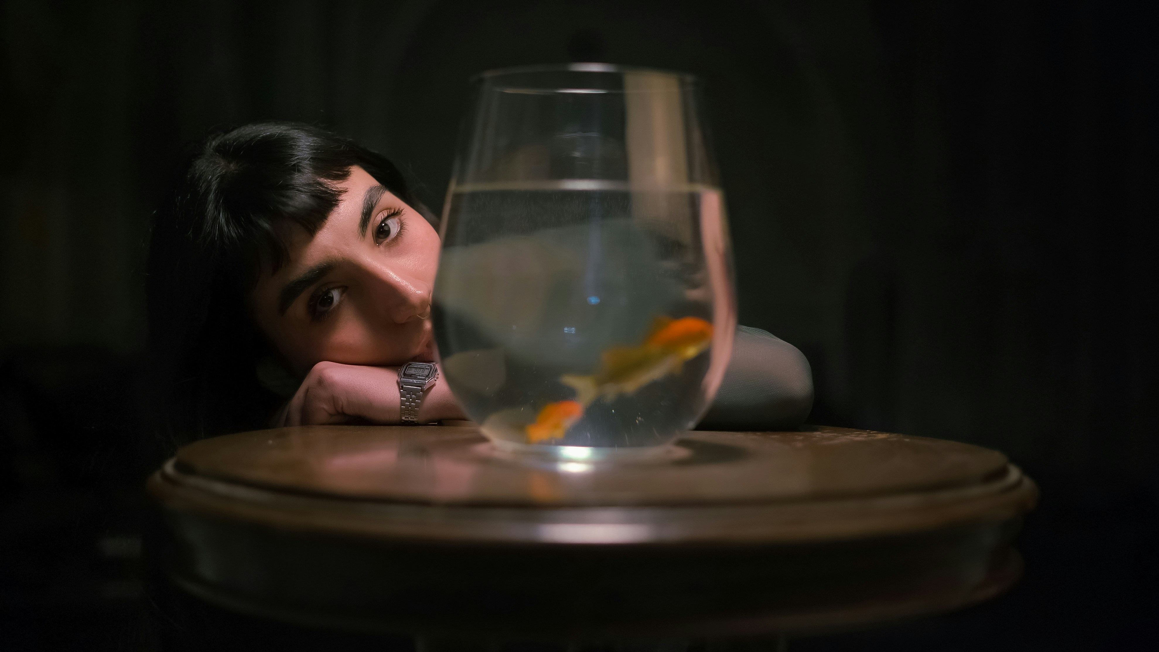 a man sitting at a table with a fish bowl in front of him