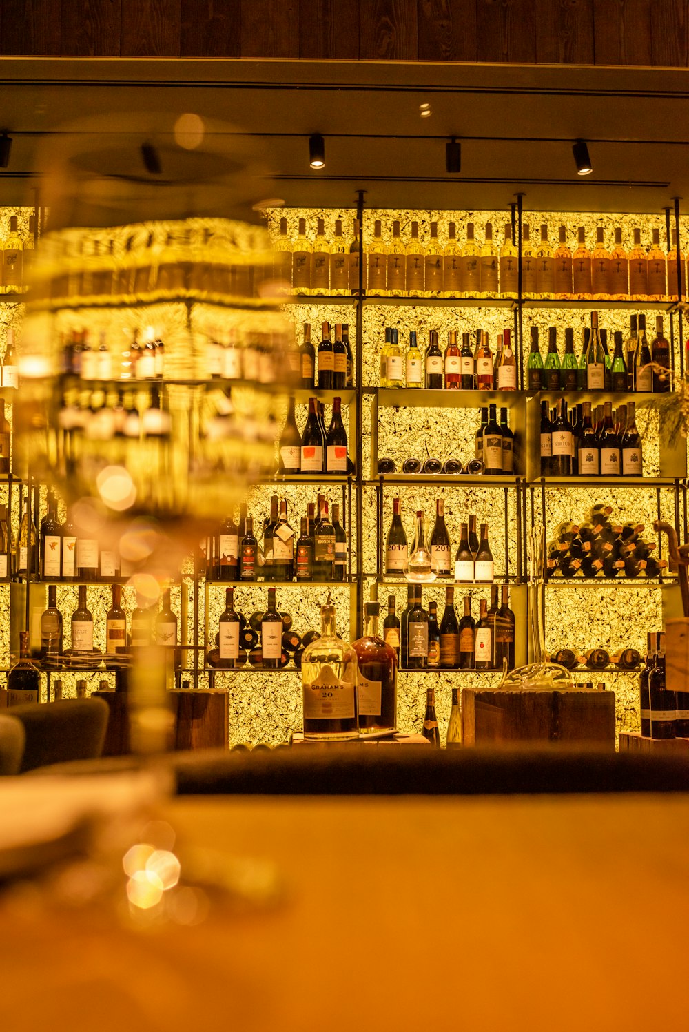 a wine glass sitting in front of a wall of bottles