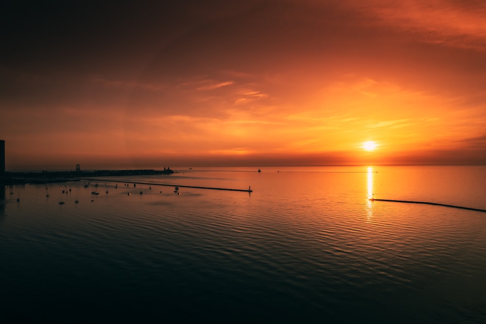 a large body of water with a sunset in the background