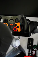 A close-up of a player gripping the steering wheel inside the XR Grand Prix simulator at Kuppajo Espresso Bar.