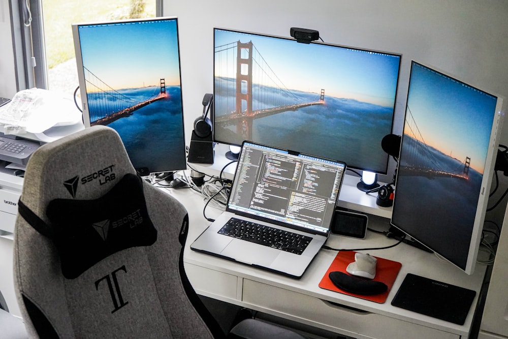 a desk with two monitors and a laptop