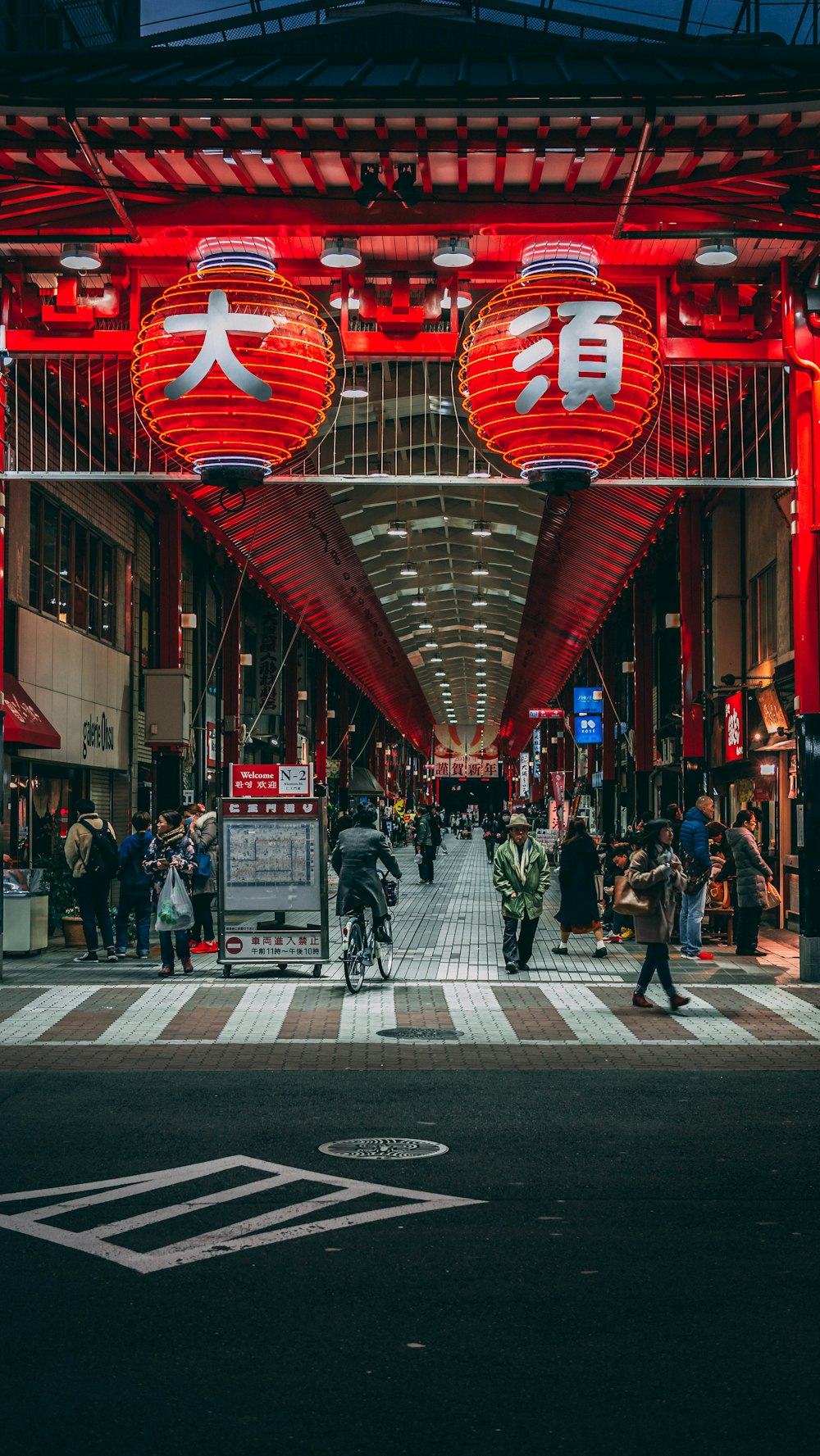 a group of people walking down a street under a red light