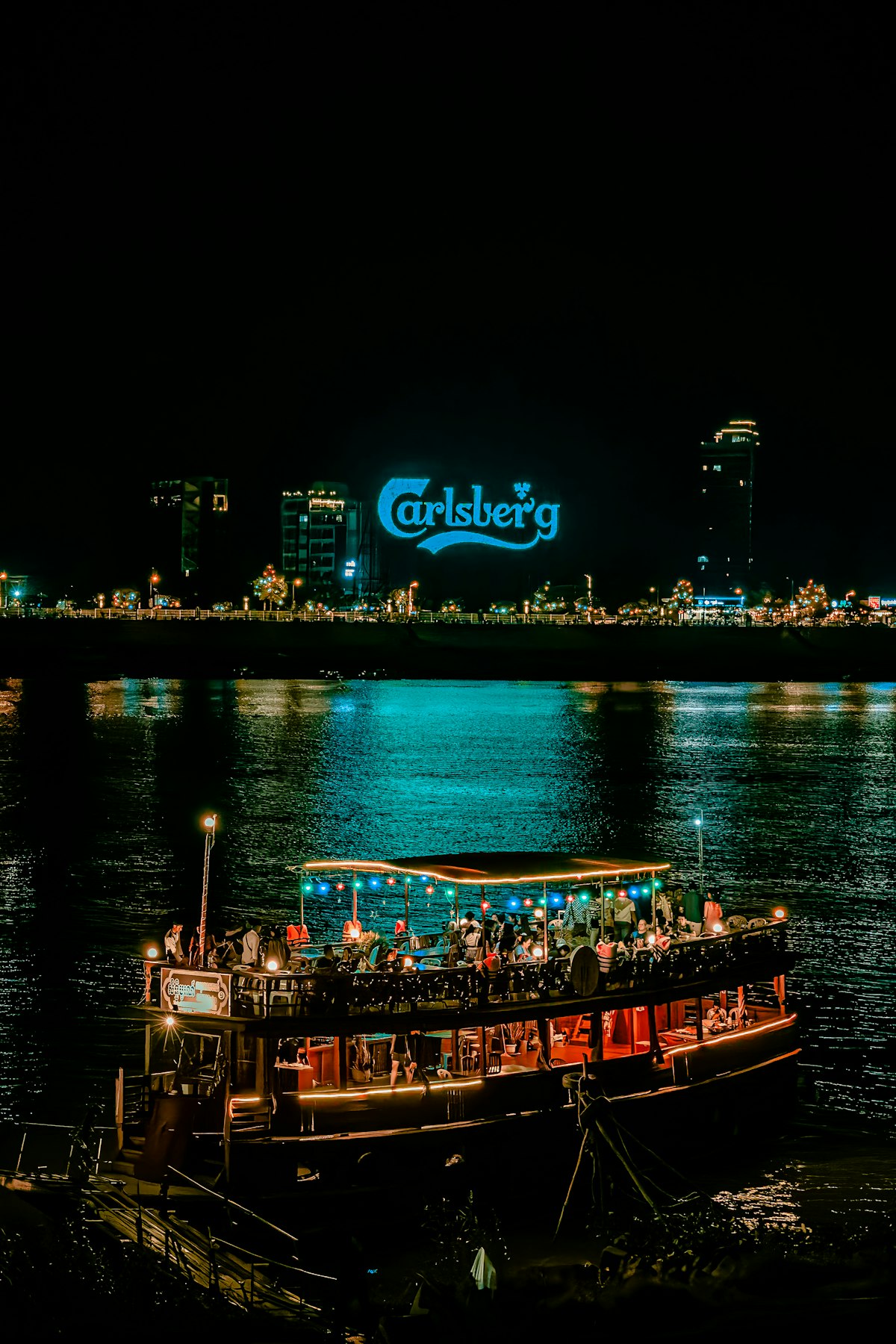 BKK1 Phnom Penh — illuminated dinner boat on the Mekong at night reflecting the expat neighbourhood's vibrant evening scene