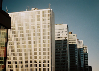 Gleaming office tower with glass exteriors under blue sky.